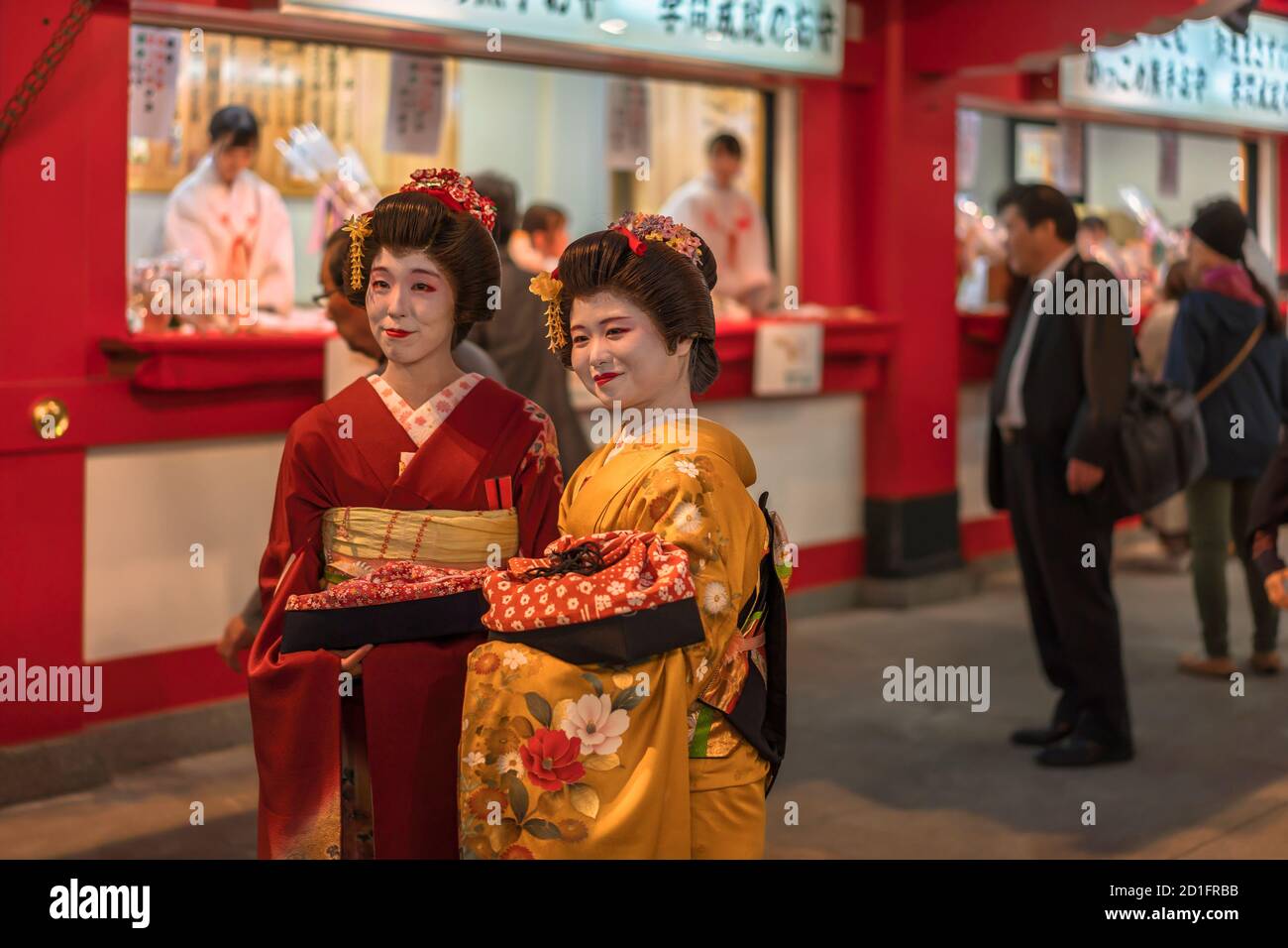 asakusa, giappone - novembre 08 2019: Due donne giapponesi che le facce sono dipinte con una polvere bianca chiamata oshiroi in posa in un kimono rosso e giallo Foto Stock