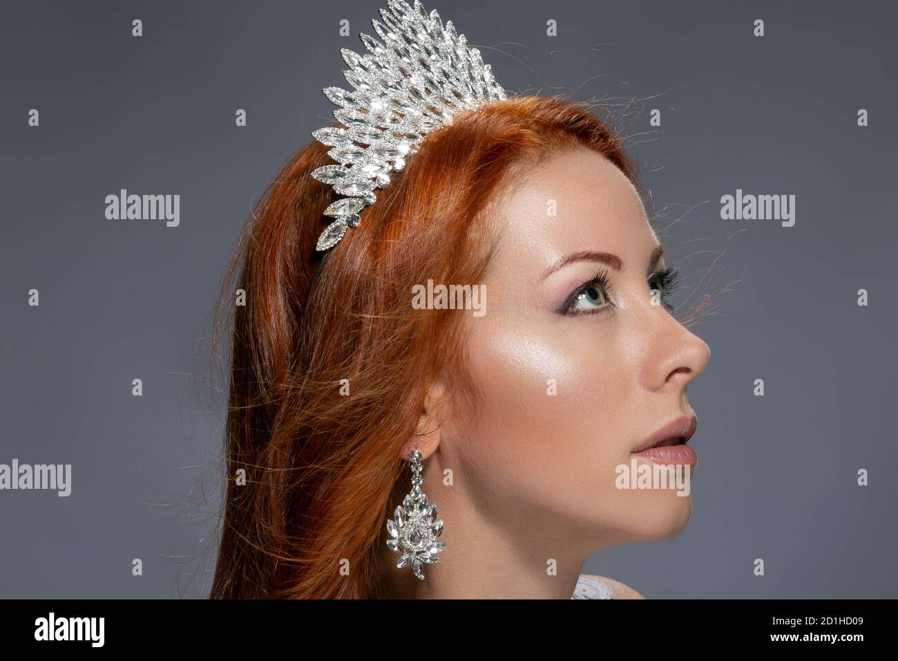 Beauty Queen. Donna di profilo con corona diamantata sulla testa rivolta verso l'alto in posizione isolata su sfondo grigio. Modello irlandese caucasico multiculturale Foto Stock
