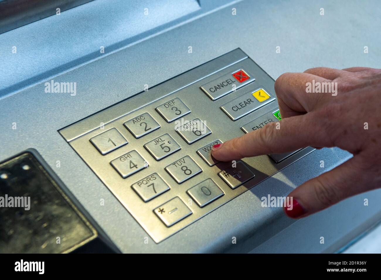 Donna che immette il suo PIN in un bancomat o in una macchina per il prelievo di denaro in Irlanda. Foto Stock