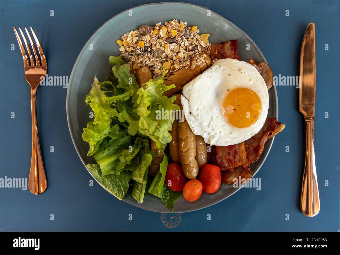 Colazione continentale con uova fritte, salsicce fritte, verdure su piatto bianco. Focalizzazione selettiva. Foto Stock