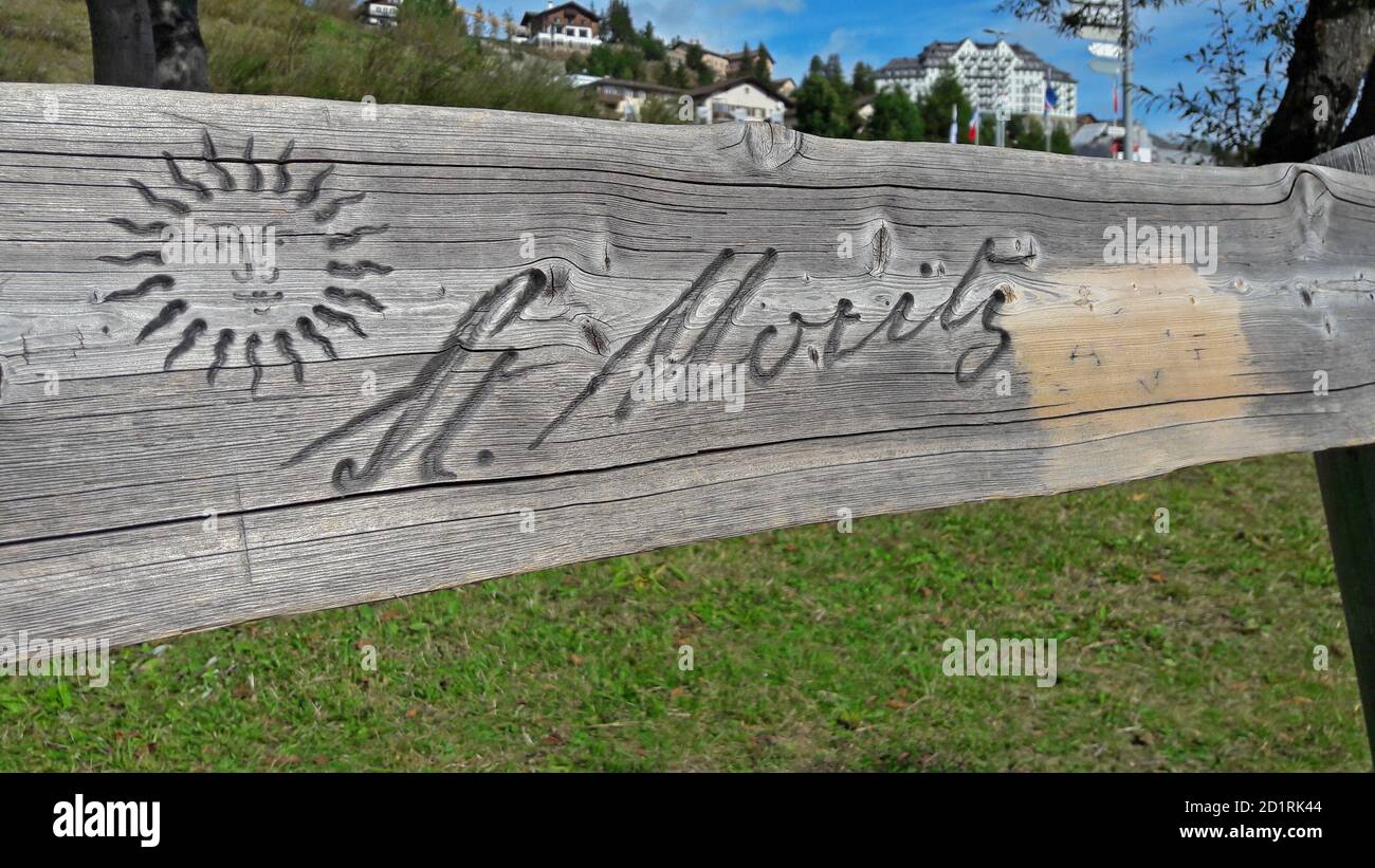 St. Moritz, Graubünden, Svizzera - 30 settembre 2020 : insegna di St. Moritz incisa su una panchina di legno con case cittadine sullo sfondo. St. Moritz Foto Stock