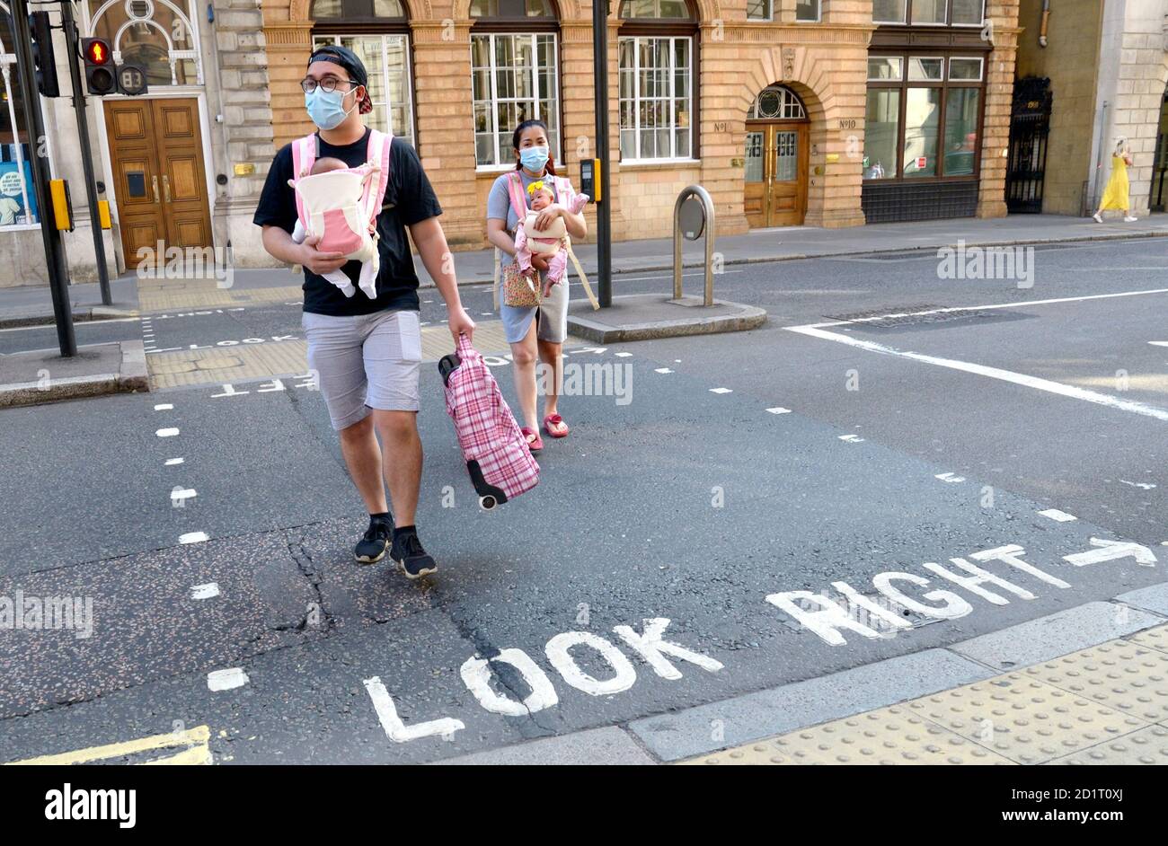 Londra, Inghilterra, Regno Unito. Giovane coppia asiatica che attraversa la strada con due bambini e maschere facciali - Settembre 2020 Foto Stock