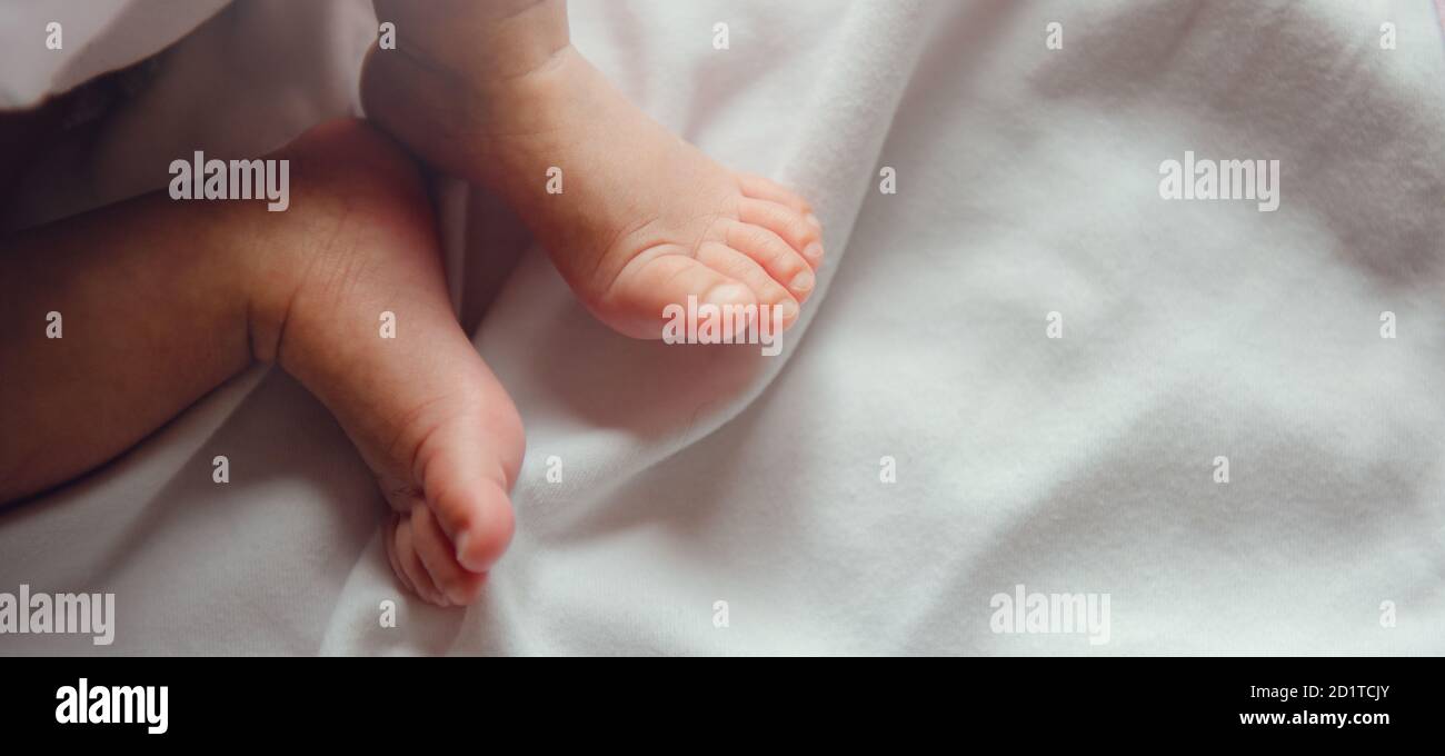 Primo piano i piccoli piedini del bambino neonato su una coperta bianca. Foto Stock