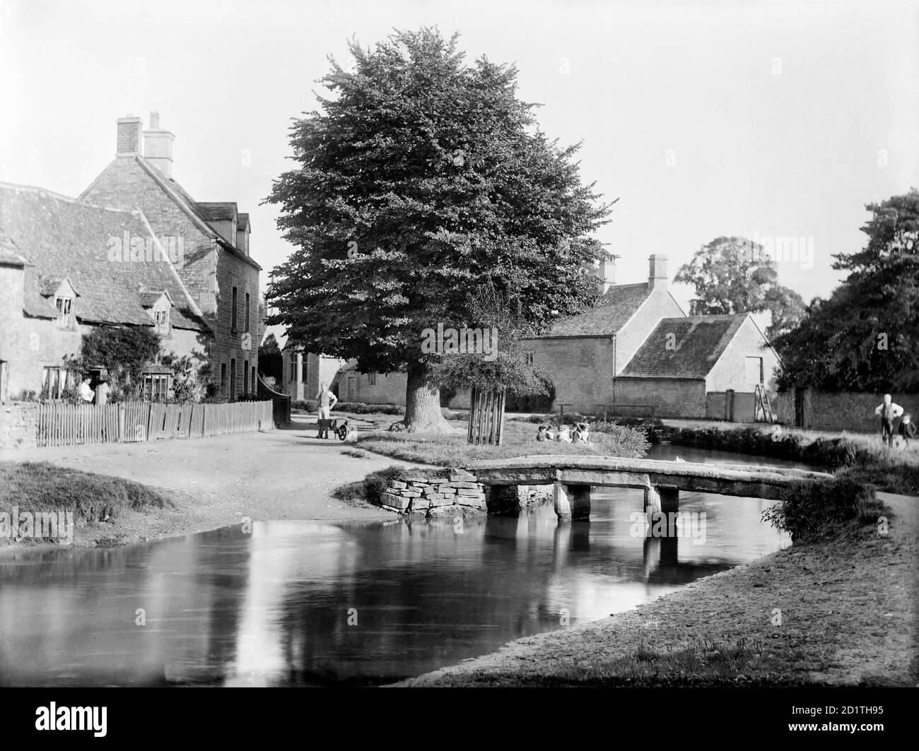 MACELLAZIONE INFERIORE, Gloucestershire. Guardando attraverso il villaggio con un piccolo ponte pedonale rustico che attraversa il fiume Eye. Fotografato nel 1890 da Henry Taunt. Foto Stock