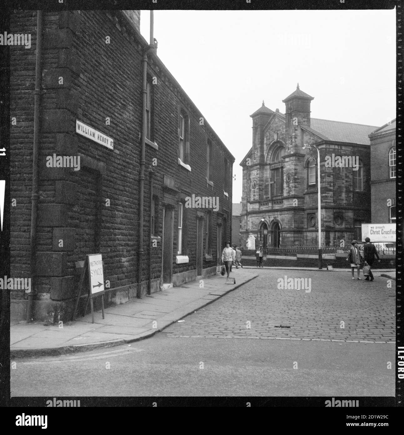 Una vista dall'incrocio di Oldham Road guardando ad ovest lungo William Henry Street verso la Chiesa Metodista della Trinità con i numeri 1, 3 e 5 in primo piano, Rochdale, Greater Manchester, UK. Foto Stock