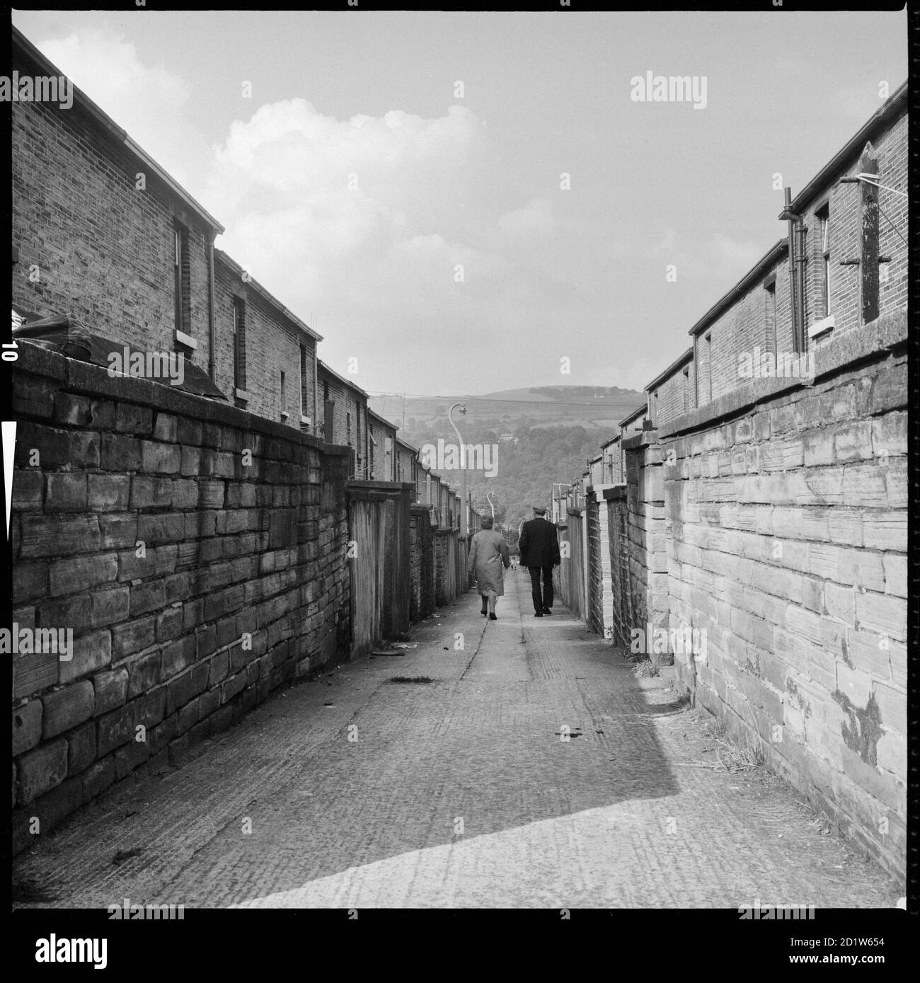 Una coppia che cammina lungo un ginnel (vicolo) che collega Caroline Street e Albert Terrace con Baidon Moor, Saltaire, Shipley, Bradford, West Yorkshire, UK. Foto Stock