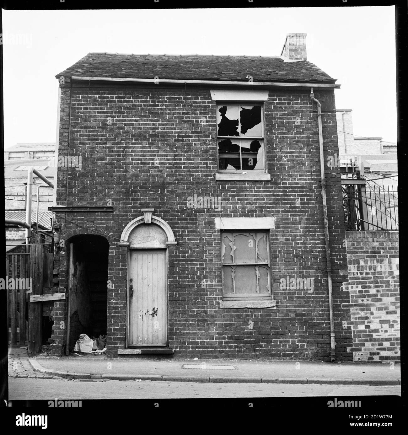 Una casa derelict con complesso industriale sullo sfondo, Stoke-on-Trent, Staffordshire, Regno Unito. Foto Stock