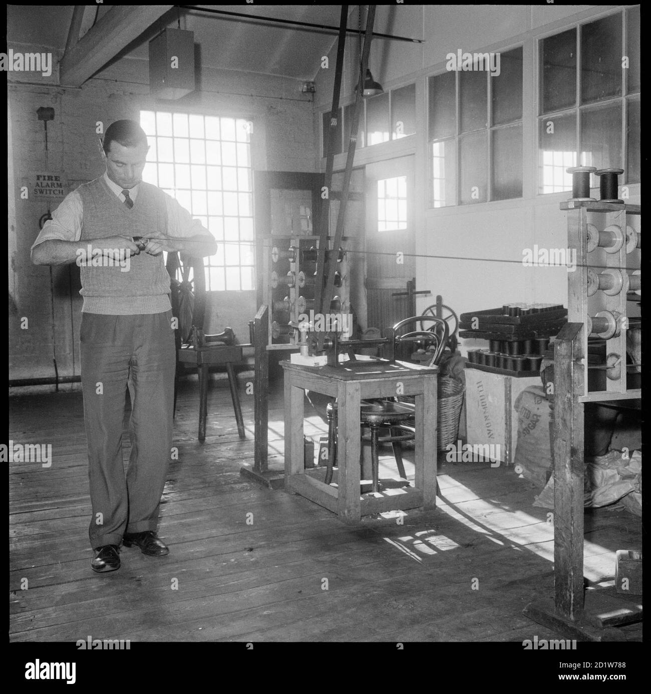 Un uomo che avvolge a mano una bobina di seta presso Bentley e Whittles Wellington Silk Mills, Strangman Street, Leek, Staffordshire Moorlands, Staffordshire, UK. Foto Stock