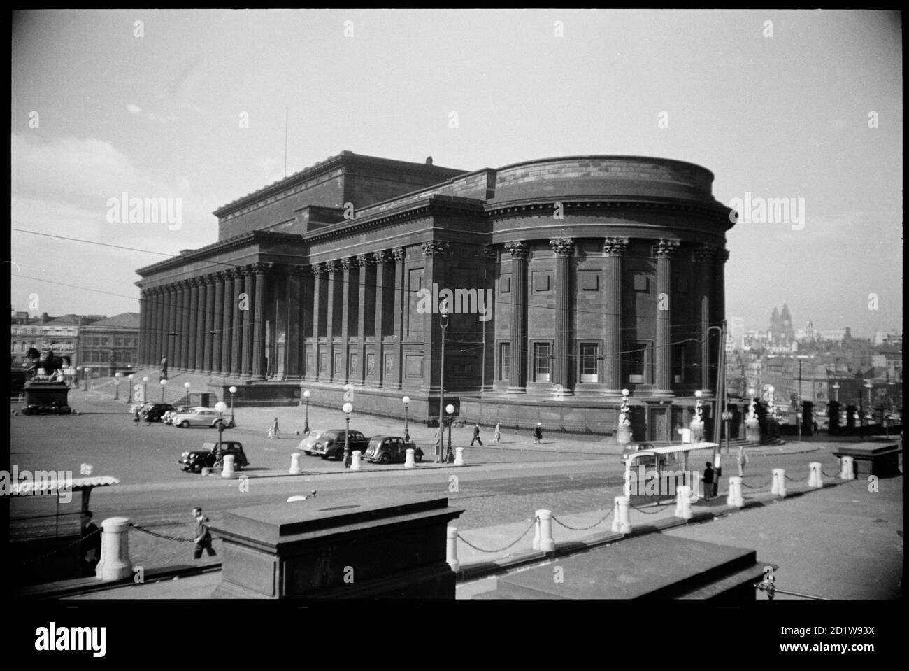Vista del fronte nord e est della St George's Hall, vista da nord, con una statua sui gradini per la sala, una statua equestre a est della sala, due cassoni ornamentali in pietra in primo piano, e una vista su Liverpool in lontananza. Foto Stock