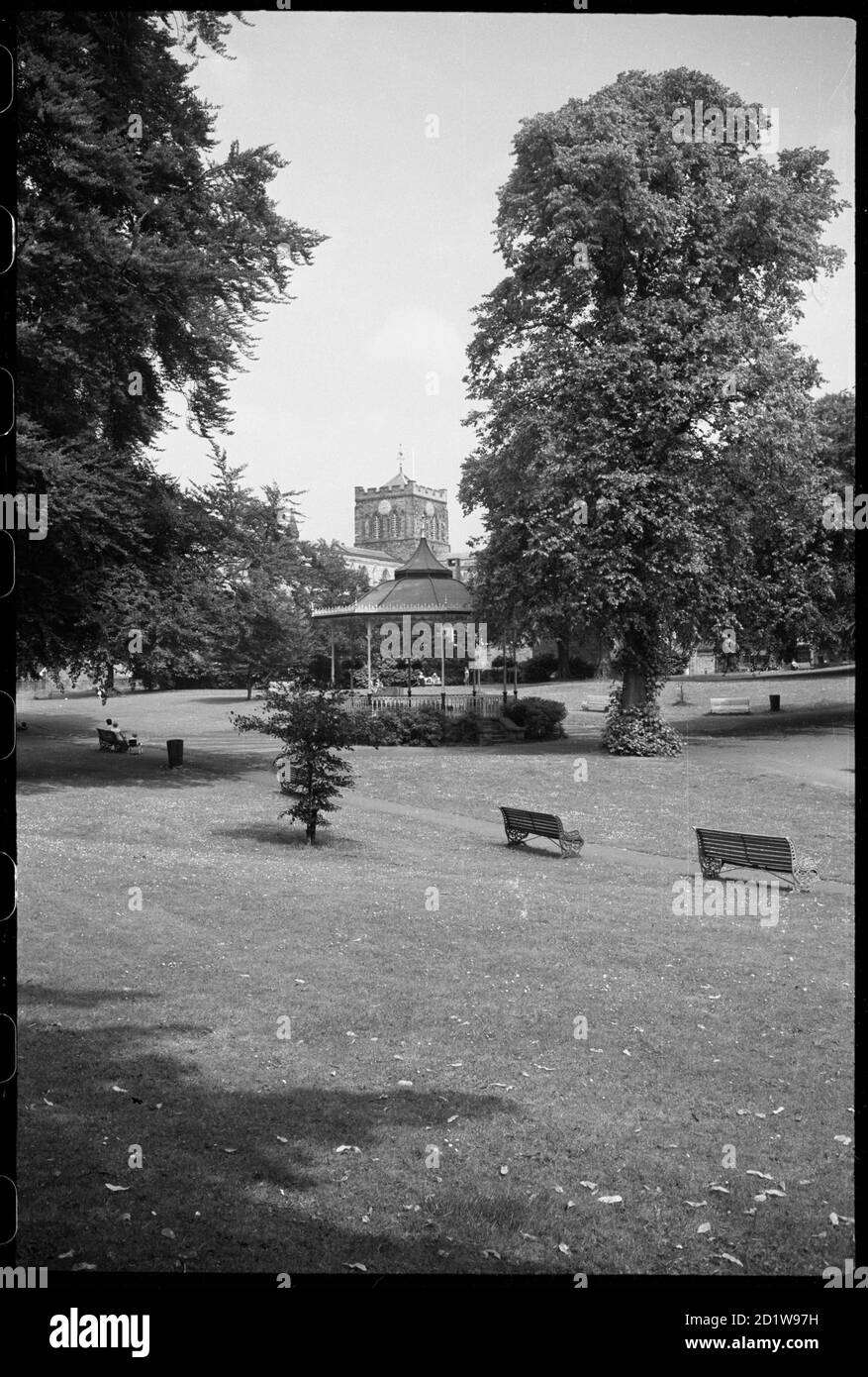 Vista generale di un chiosco a bands dei primi del 20 ° secolo in un parco, celled il Sele, con una vista parziale dell'Abbazia di Hexham con torre di attraversamento sullo sfondo. Foto Stock