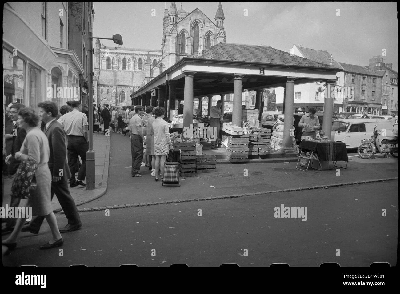 Vista generale della Piazza del mercato, che mostra gli Shambles, un mercato coperto eretto nel 1766, con venditori e acquirenti in primo piano, e l'elevazione est della Chiesa del Priorato di Sant'Andrea sullo sfondo. Foto Stock