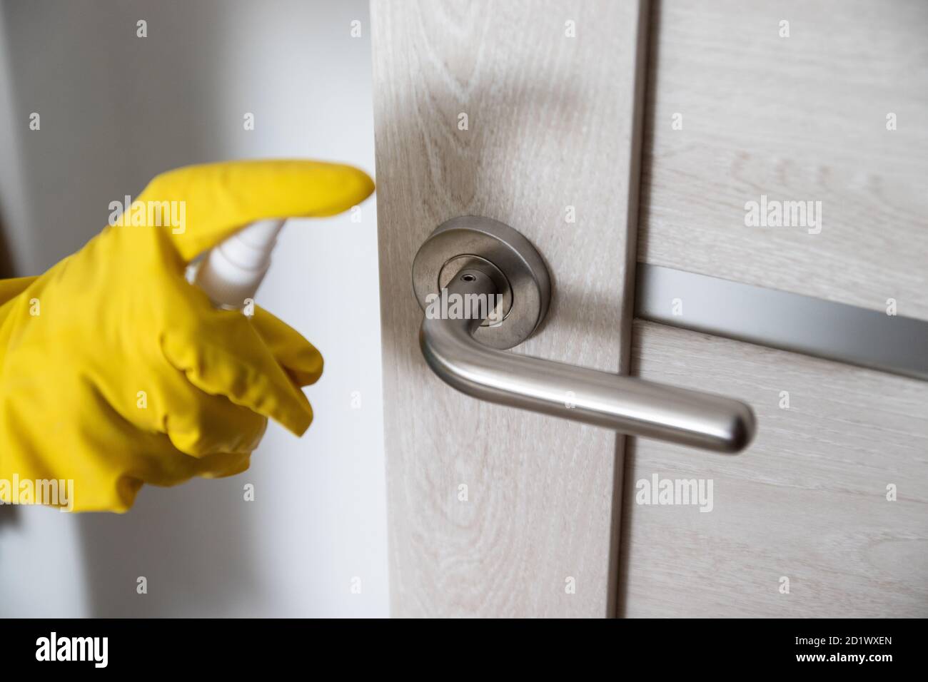 Coronavirus COVID-19, Donna mano che usa alcool spray o antisettico per pulire la manopola della porta per uccidere il virus corona su superfici a contatto o a contatto con il pubblico Foto Stock