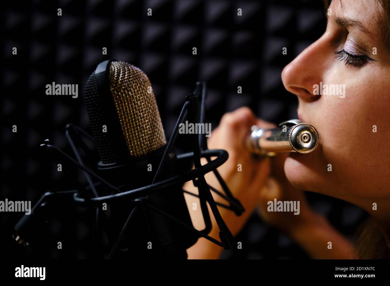 Girl flauto in cuffie player gioca in studio di registrazione, primo piano.  Registra strumenti musicali a vento con un microfono professionale. Donna  flutista pla Foto stock - Alamy