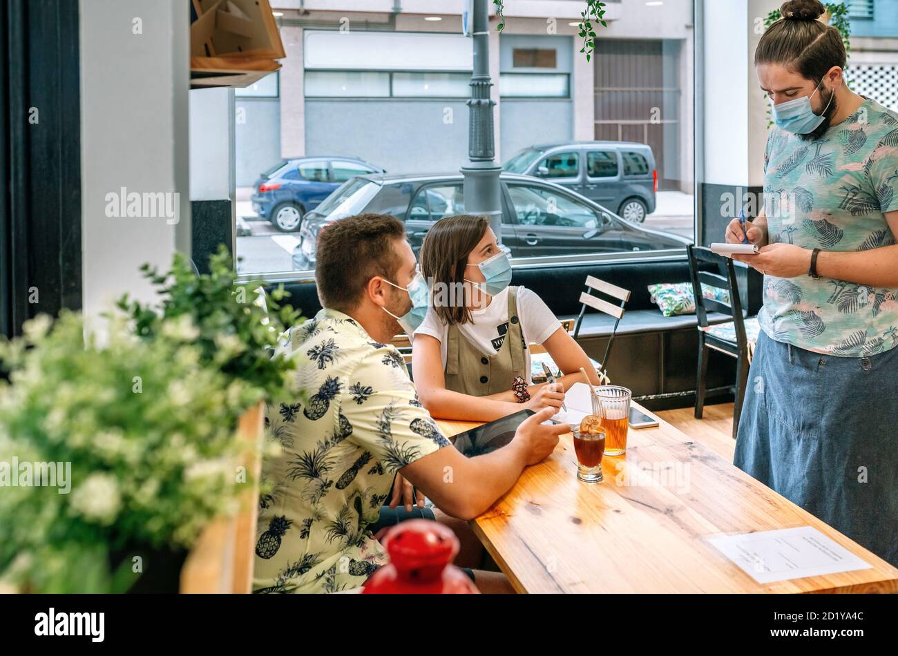 Accoppia con maschera facendo ordine di cibo al cameriere Foto Stock