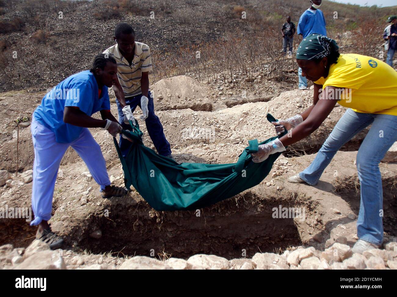 La gente porta un cadavere in una tomba di massa a Titanyen, dove decine di migliaia di corpi sono già stati sepolti dopo il terremoto, fuori di Port au Prince, Haiti 25 febbraio 2010. Ogni giorno una dozzina di cadaveri trovati sotto le macerie o dall'Ospedale Generale sono sepolti nella tomba di massa di Titanyen. REUTERS/St-Felix Evens (HAITI - Tag: IMMAGINI DEL GIORNO IN CASO DI DISASTRO) Foto Stock