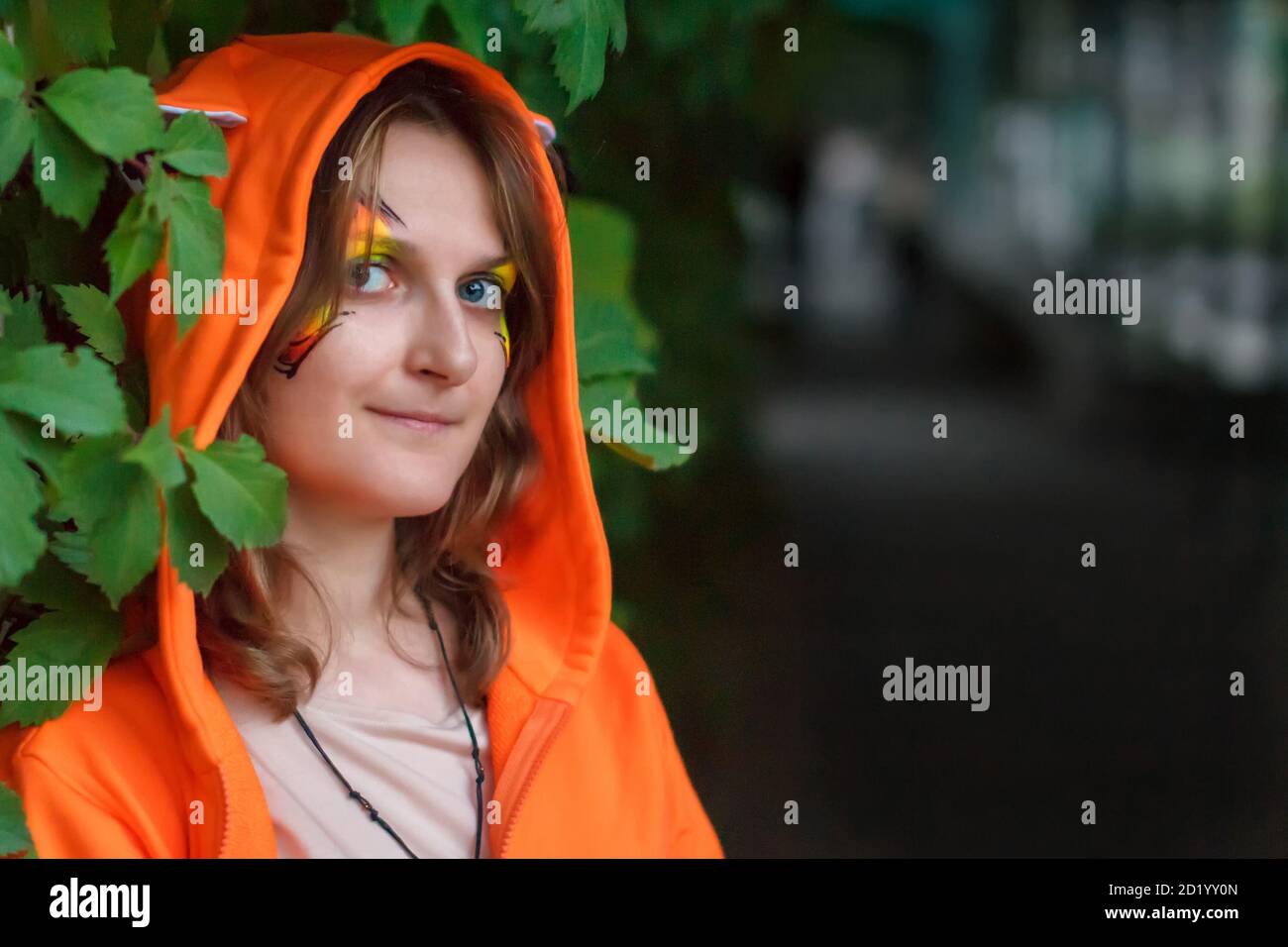 Donna insolitamente vestita con una leggera follia negli occhi. Una ragazza in un costume da eroe fantasy e l'oscurità di un lungo corridoio. Ritratto femminile con Foto Stock