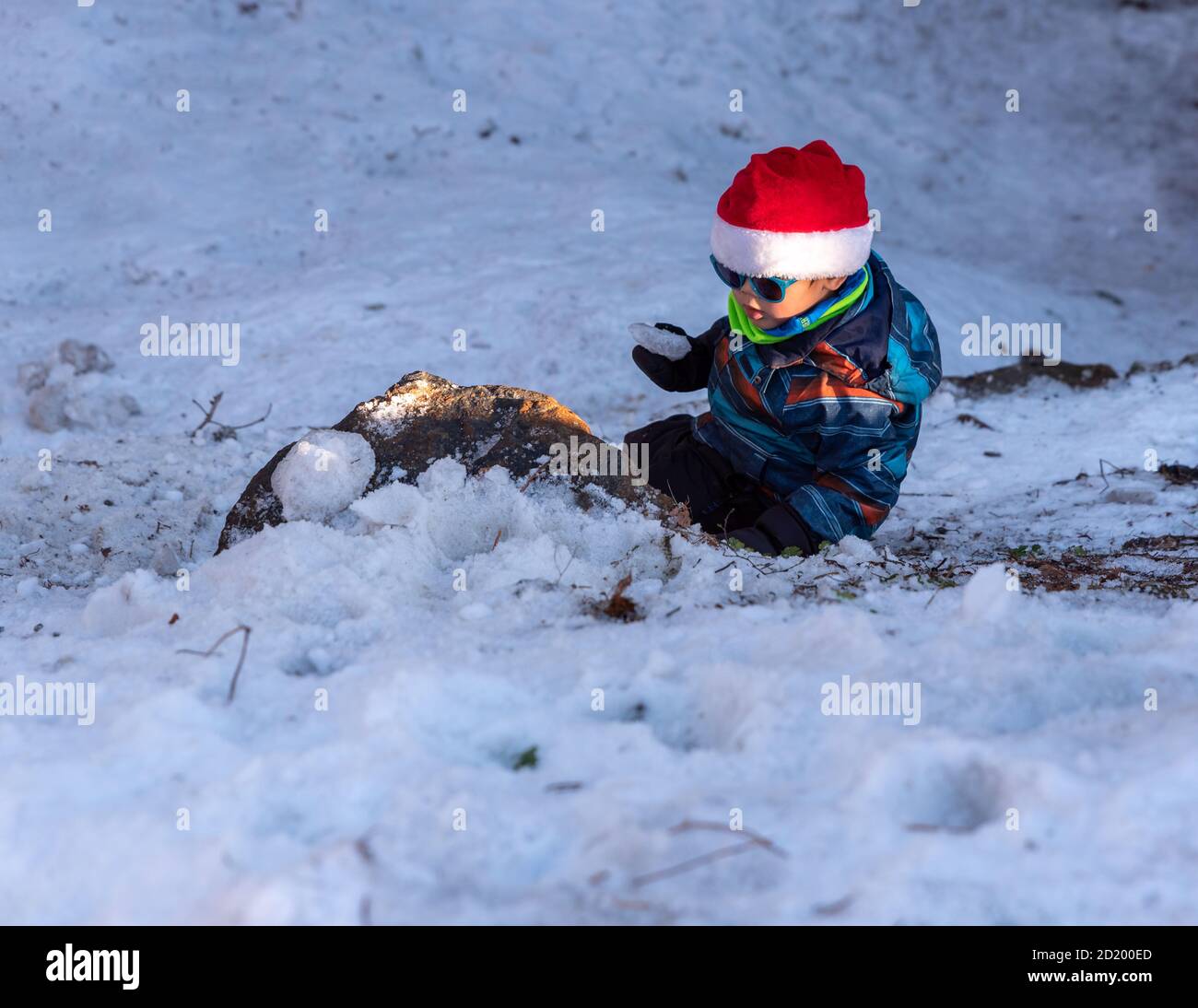 Ragazzo con cappello rosso Babbo Natale su uno sfondo di paesaggio invernale. Felice bambino sorridente che gioca nella neve a Natale. Crans Montana in Svizzera. Foto Stock