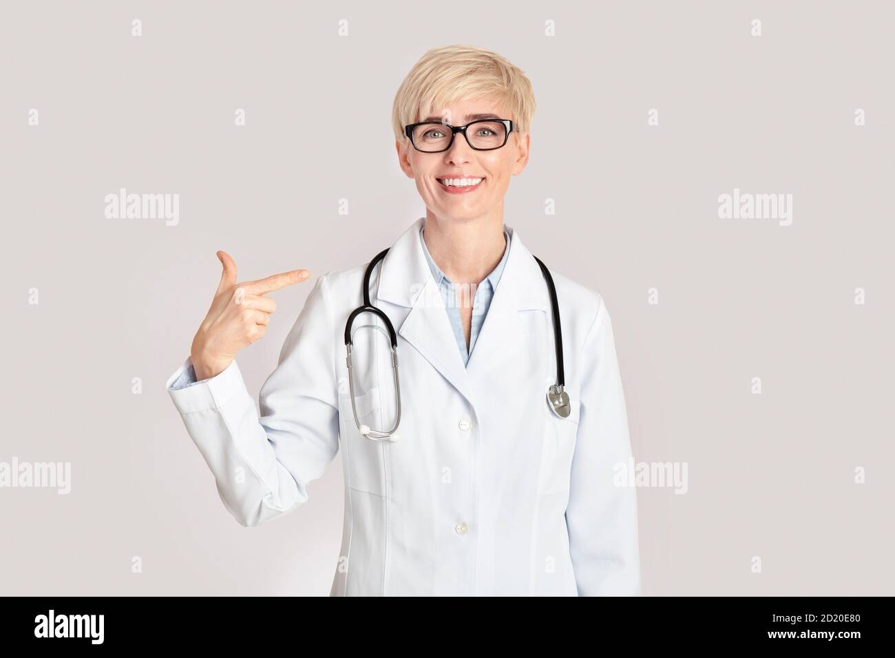 Professionisti medici e prevenzione delle malattie. Sorridente medico donna di mezza età si punta con il dito Foto Stock