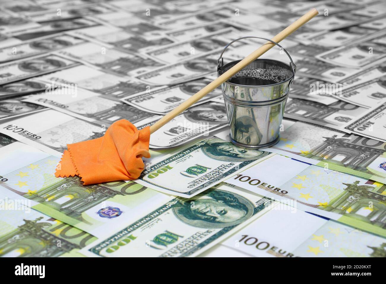 Riciclaggio di denaro. Il concetto di corruzione. Un secchio d'acqua e un mop con un cavalletto di straccio sul dollaro e le banconote in euro. Soldi puliti e sporchi. Foto Stock