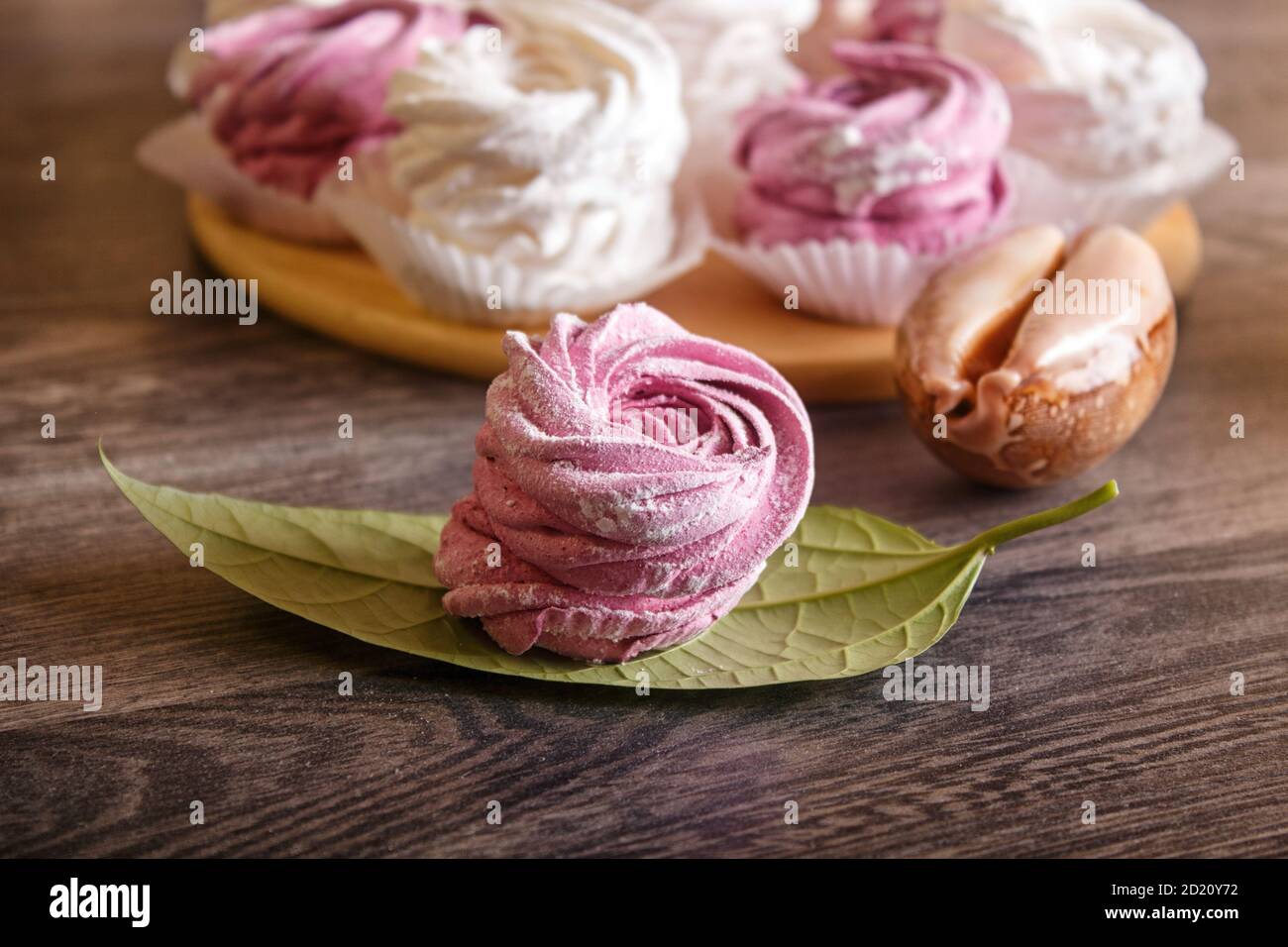 marshmallow fatti in casa rosa e bianco (zephyr) su un legno rotondo tavola con conchiglie su sfondo grigio di legno Foto Stock
