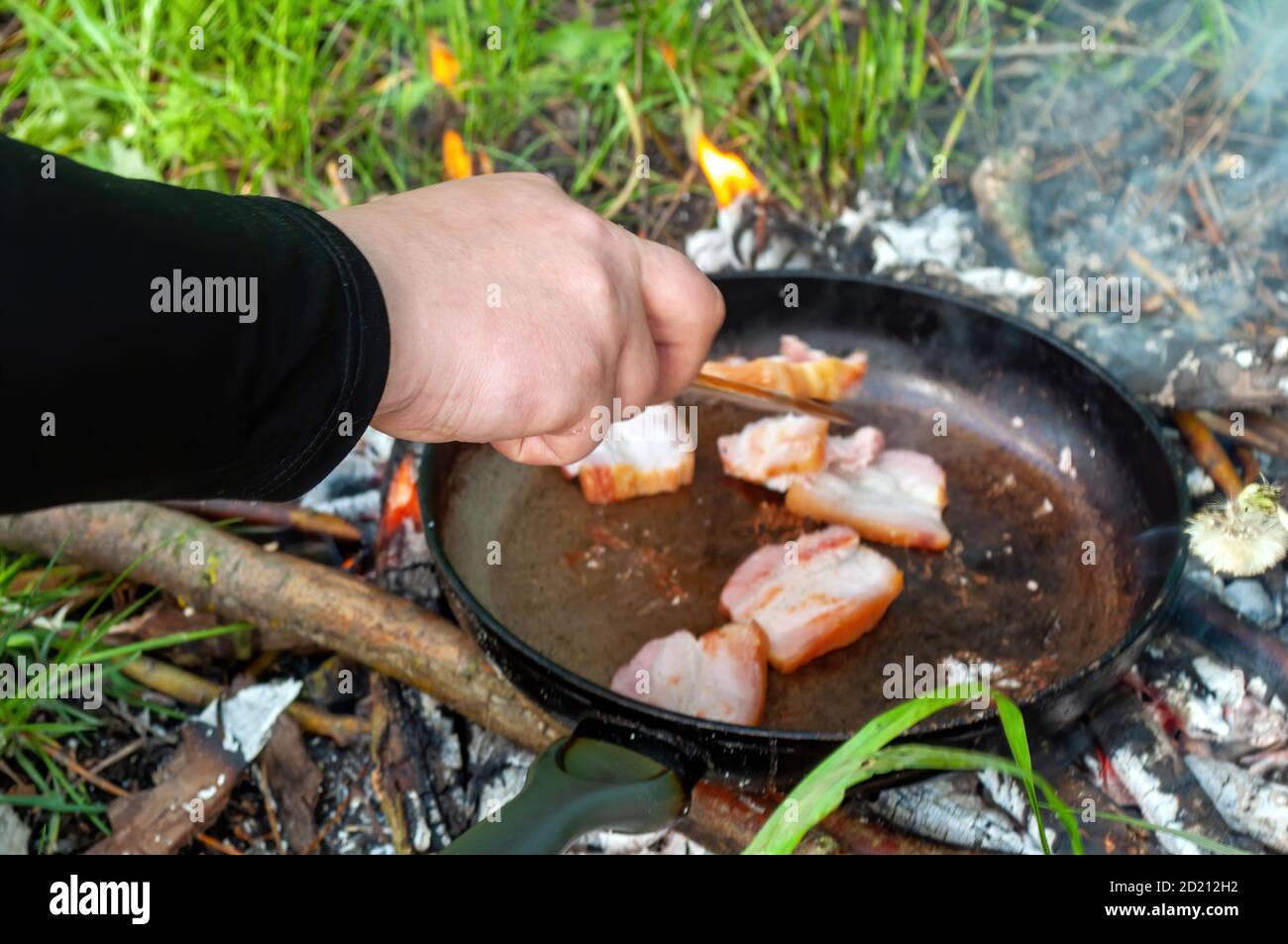 cucina all'aperto in padella con una spatola e una mano dell'uomo. barbecue. foto Foto Stock