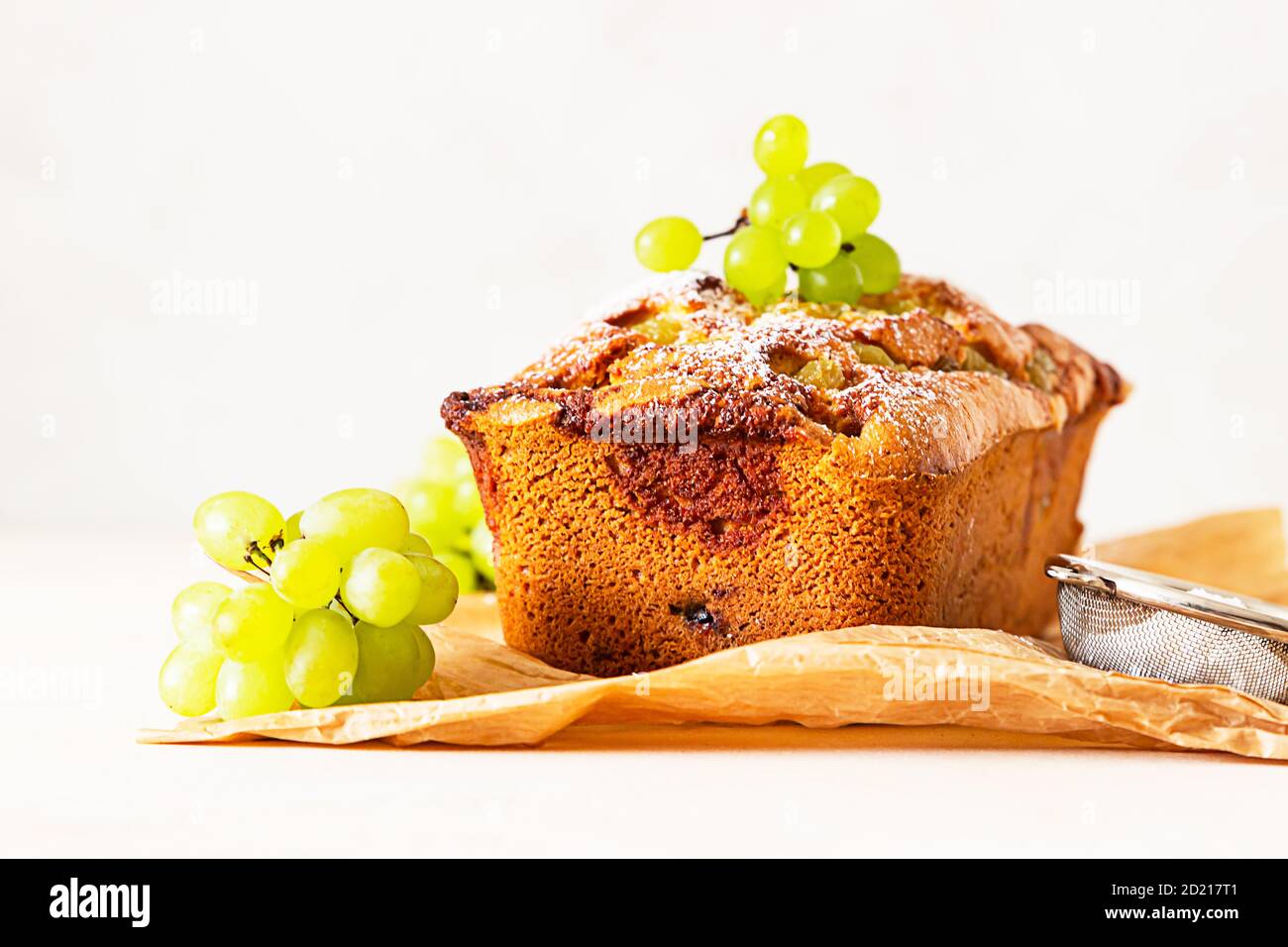 Deliziosa torta fatta in casa con timo e zucchero in polvere su carta pergamena. Sfondo di pietra chiaro. Foto Stock