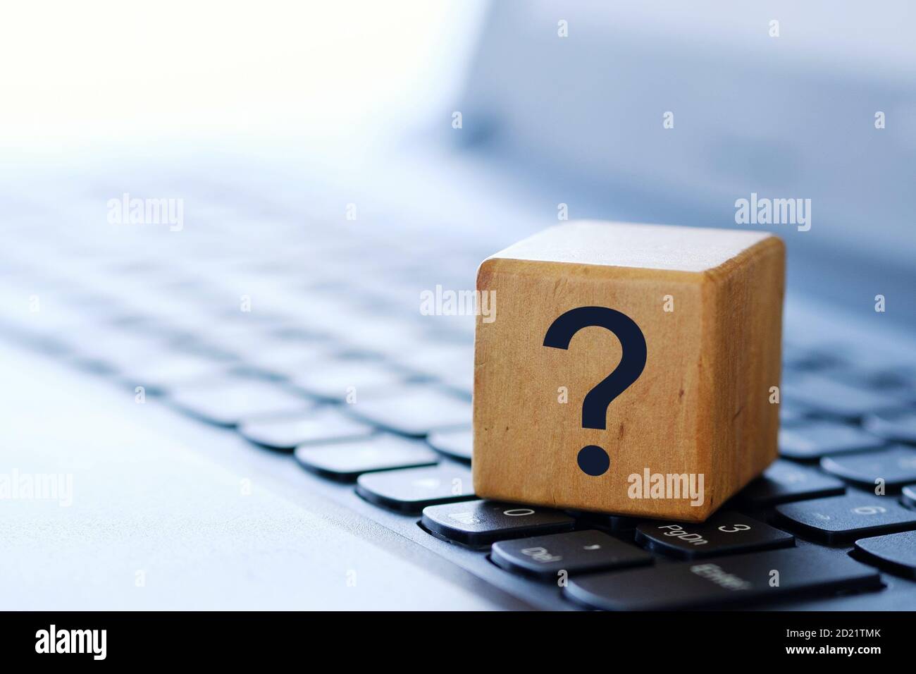 Un punto interrogativo su un cubo di legno sulla tastiera di un computer, con uno sfondo sfocato e una profondità di campo poco profonda. Foto Stock