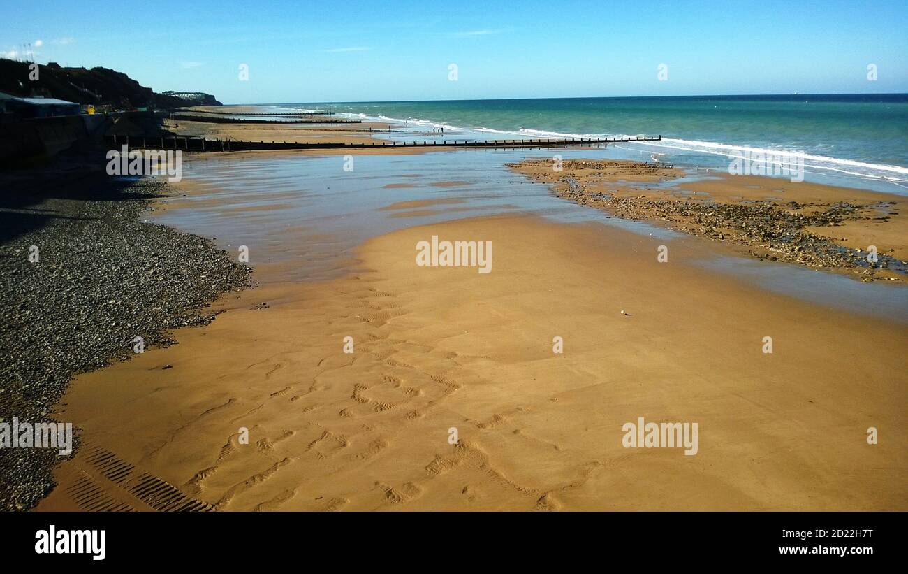Vista panoramica dal molo di Comer a Norfolk East Anglia of Bella spiaggia di sabbia e oceano a bassa marea in estate senza gente e cielo blu calmo Foto Stock