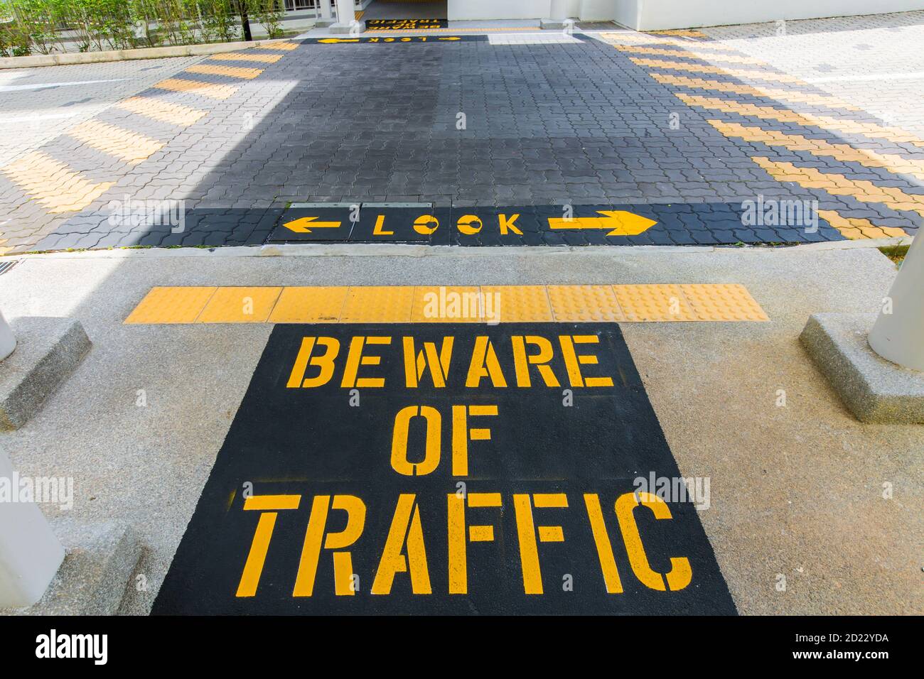 Big dicings cartello giallo dipinto 'attenzione al traffico' a terra, le persone sono tenute a controllare qualsiasi veicolo in arrivo prima di attraversare la strada. Foto Stock