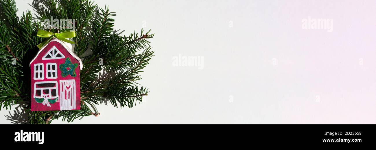 Banner di Natale con casa in legno rosso e rami di abete rosso, colorato, idee regalo. fai da te. Buon disegno di fotoricettore per l'agenzia immobiliare. Foto Stock