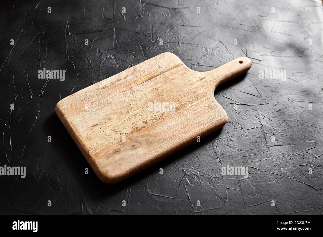 Un tagliere con manico su tavolo in pietra nera. Tagliere in legno di pino  vuoto su sfondo scuro, vista laterale Foto stock - Alamy