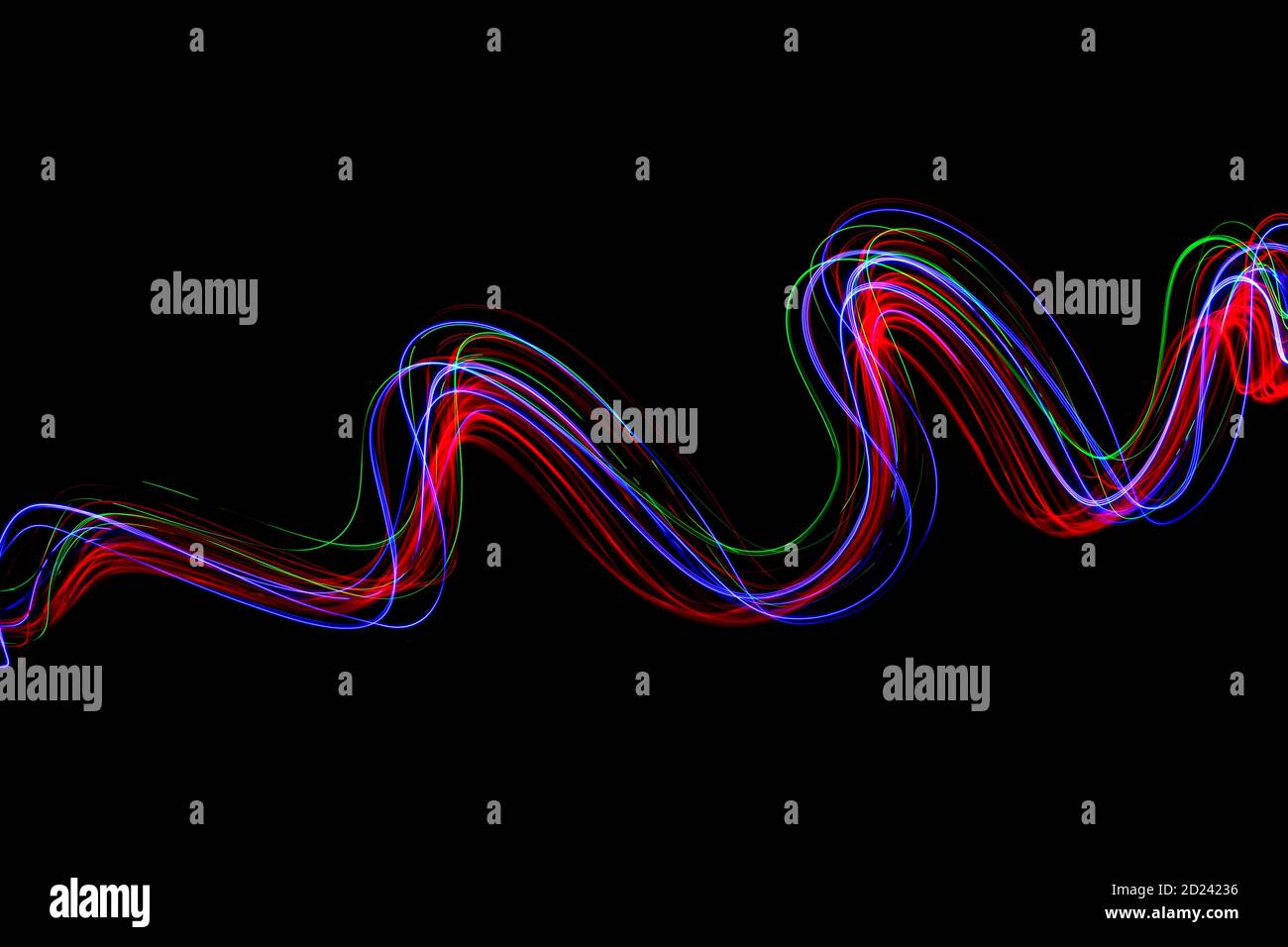 Una lunga esposizione fotografia di neon di colore in un astratto turbolenza, linee parallele configurazione contro uno sfondo nero. La pittura di luce la fotografia. Foto Stock