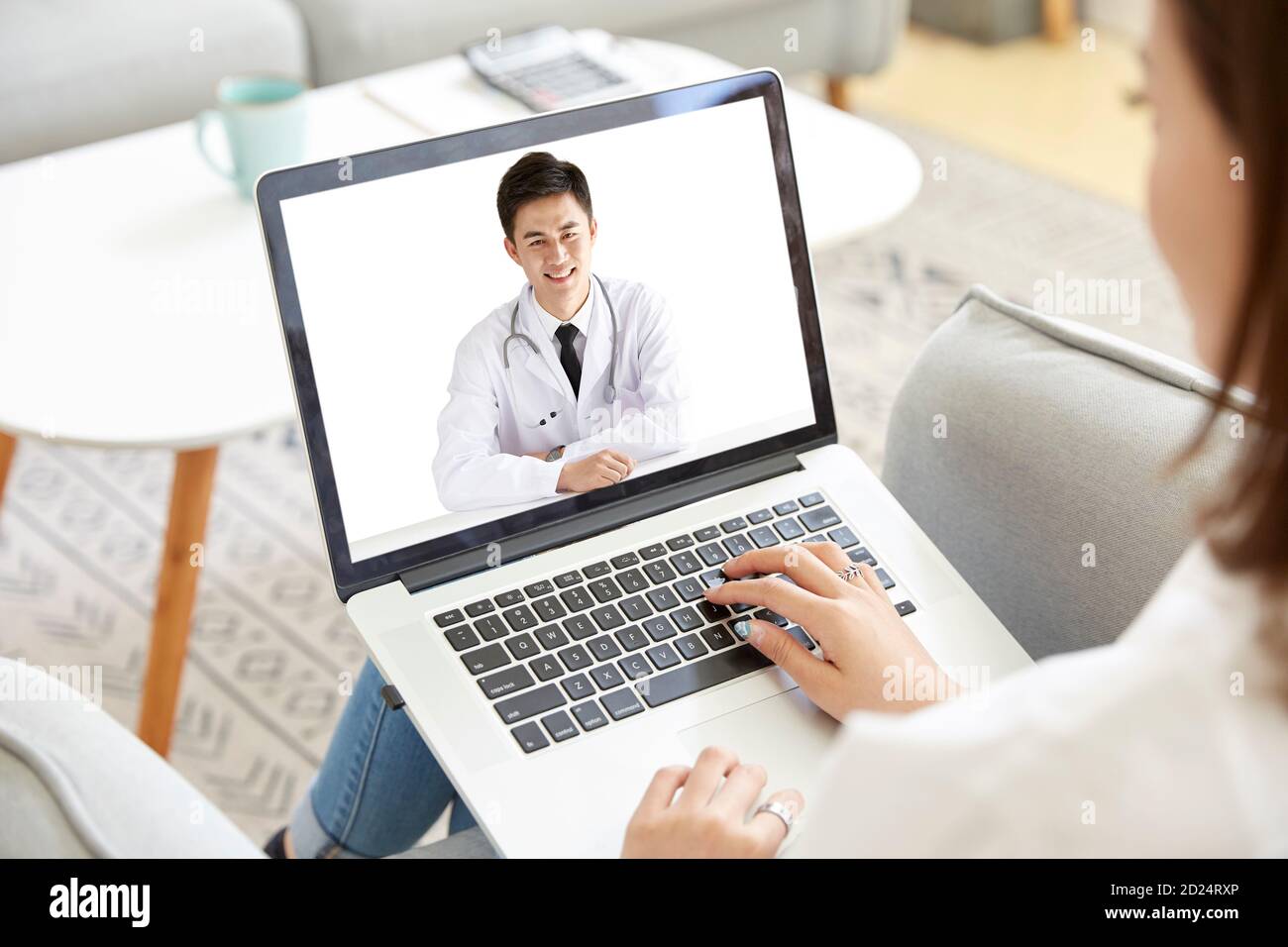 giovane donna asiatica che rimane a casa consultando un medico via videochiamata con un computer portatile Foto Stock