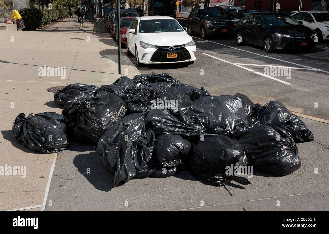 un mucchio di sacchetti pieni di plastica di immondizia che siedono su un angolo di new york city street in attesa del prelievo Foto Stock