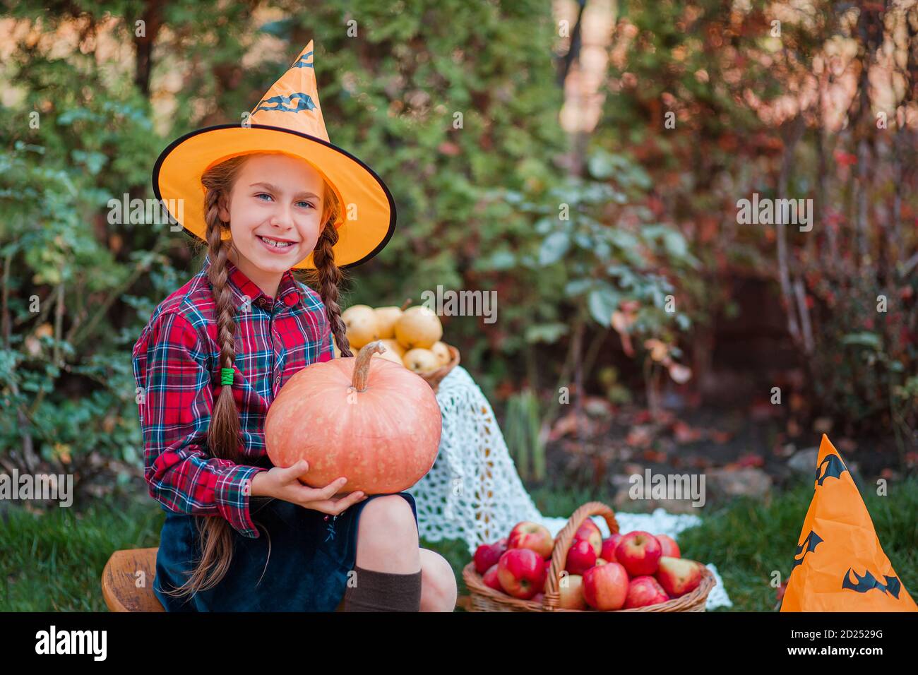 Carino bambina abbraccia una zucca in giardino d'autunno. Celebrando raccolto autunnale. Foto Stock
