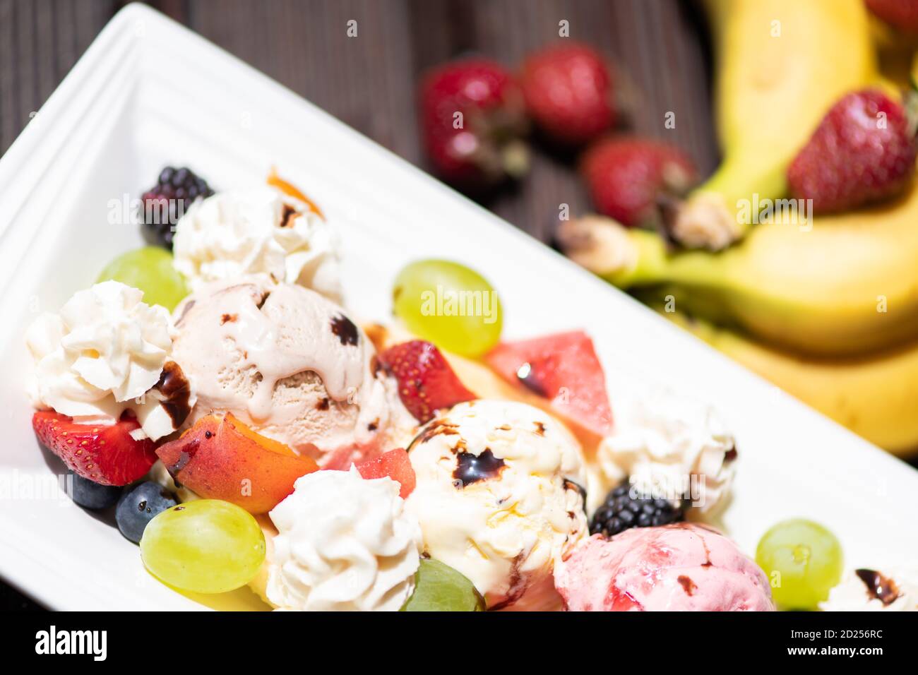 Piatto di sana Macedonia di frutta fresca con gelato su fondo di legno. Foto Stock