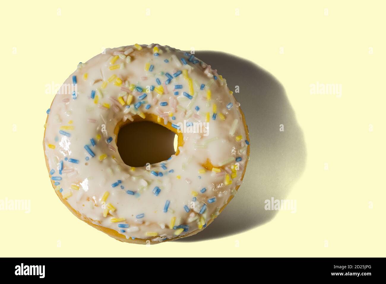 Vista della ciambella cosparsa di smalto multicolore isolato su sfondo giallo. Concetto di cibo e bevande. Foto Stock
