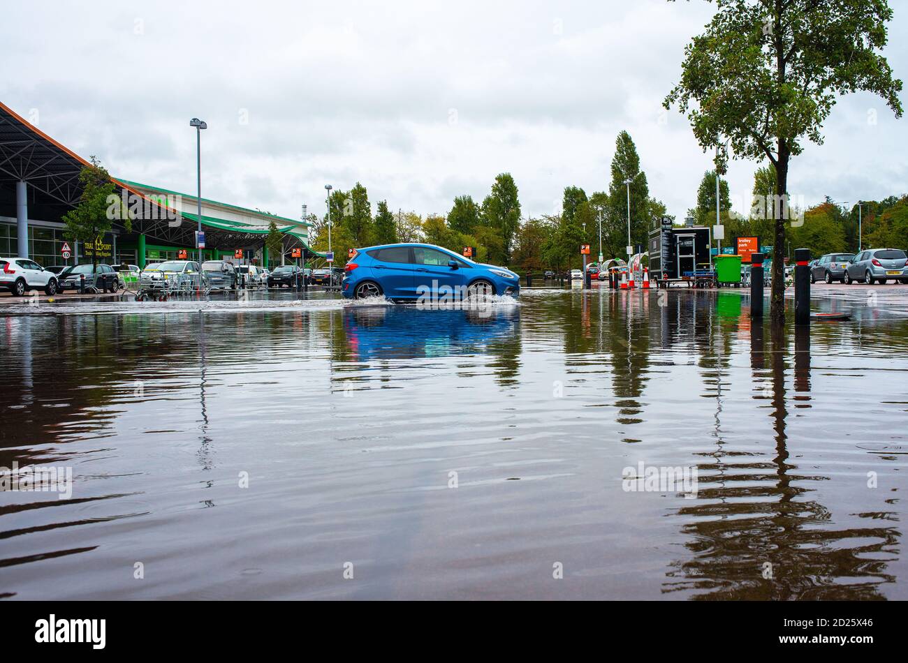 Parcheggio al dettaglio sommerso dopo forti downpoours. L'alluvione ha reso pericolosa la guida con alcuni proprietari di auto incapaci di accedere ai loro veicoli. Foto Stock