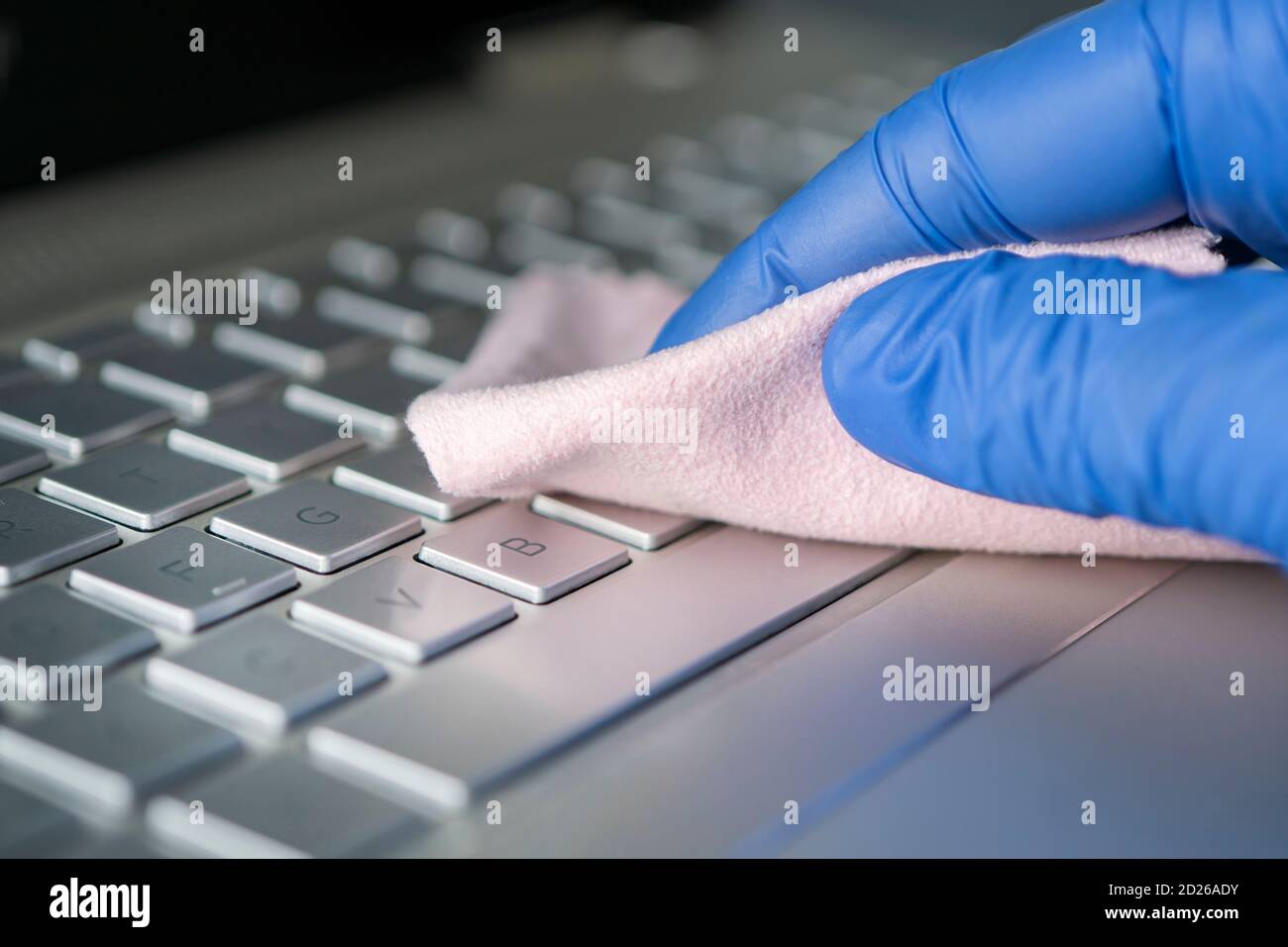 misure disinfettanti per la protezione contro il coronavirus o altri microbi. prevenzione dell'infezione virale. mano in un guanto blu con un primo piano di straccio rosa Foto Stock