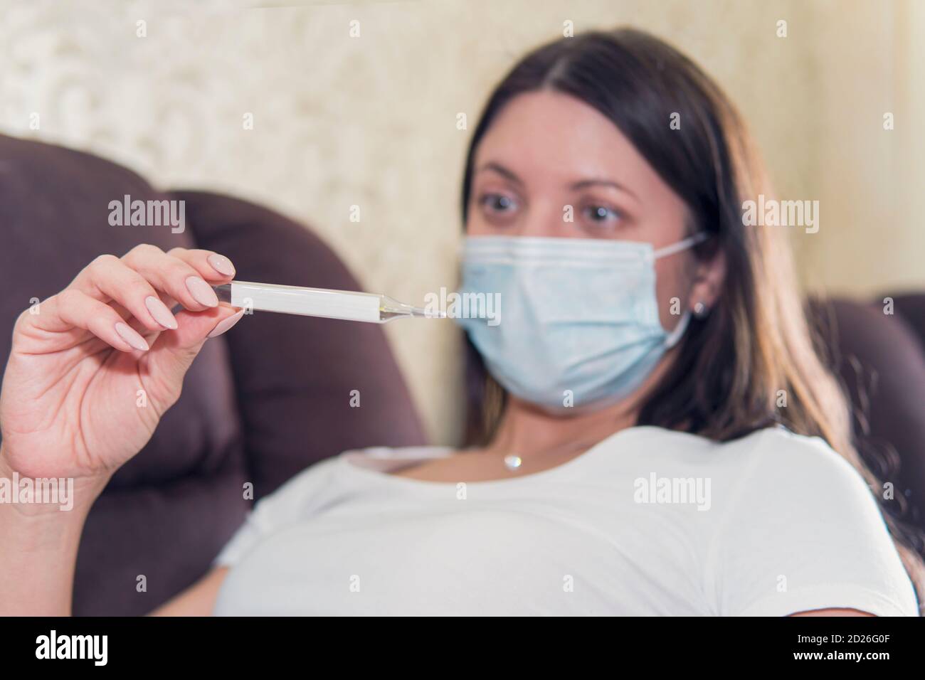 Ragazza con respiro corto sintomo di Coronavirus. Controllare la febbre. COVID-19 Pandemic Coronavirus febbre Donna controllo termometro Home Foto Stock