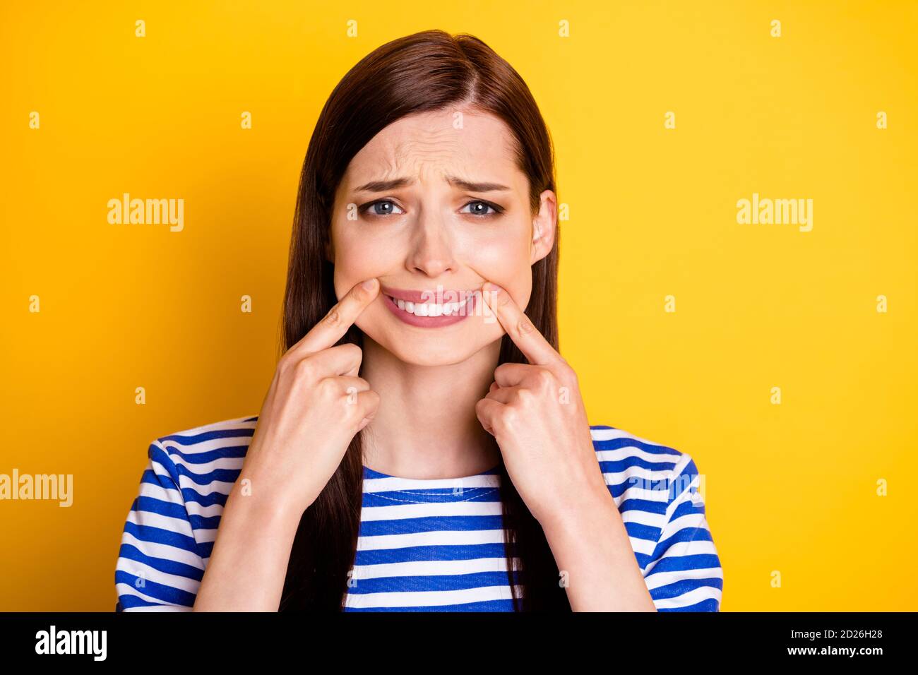 Ritratto di una donna malinconica frustrato toccare dita bocca labbra nascondi dolore rendere falso sorriso toothy indossare bello elegante alla moda vestiti Foto Stock