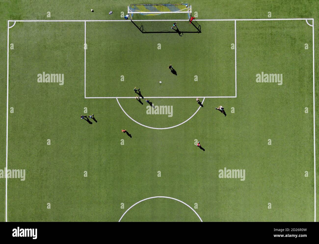 Giocatori di calcio che giocano una partita su un campo sportivo verde vista direttamente dall'alto da un drone su un soleggiato giorno d'estate Foto Stock
