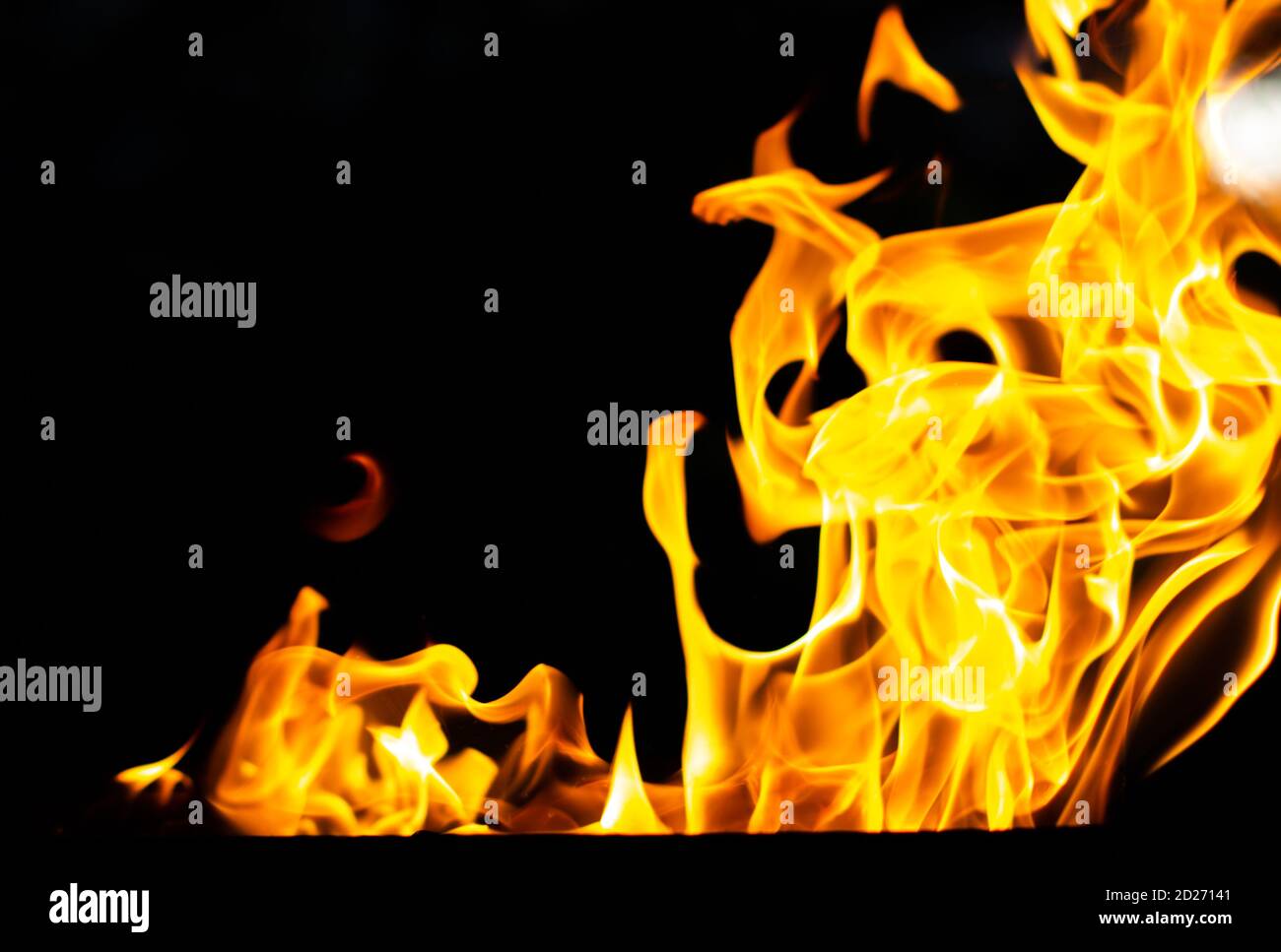 Fiamma di fuoco, arancione saturo lampeggia su sfondo nero. Astratte lingue di fiamma nel buio per il design Foto Stock