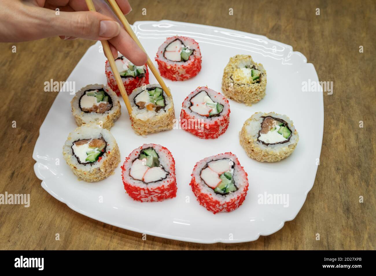 Vari sushi giapponesi su piatto bianco con bastoncini di legno sfondo Foto Stock