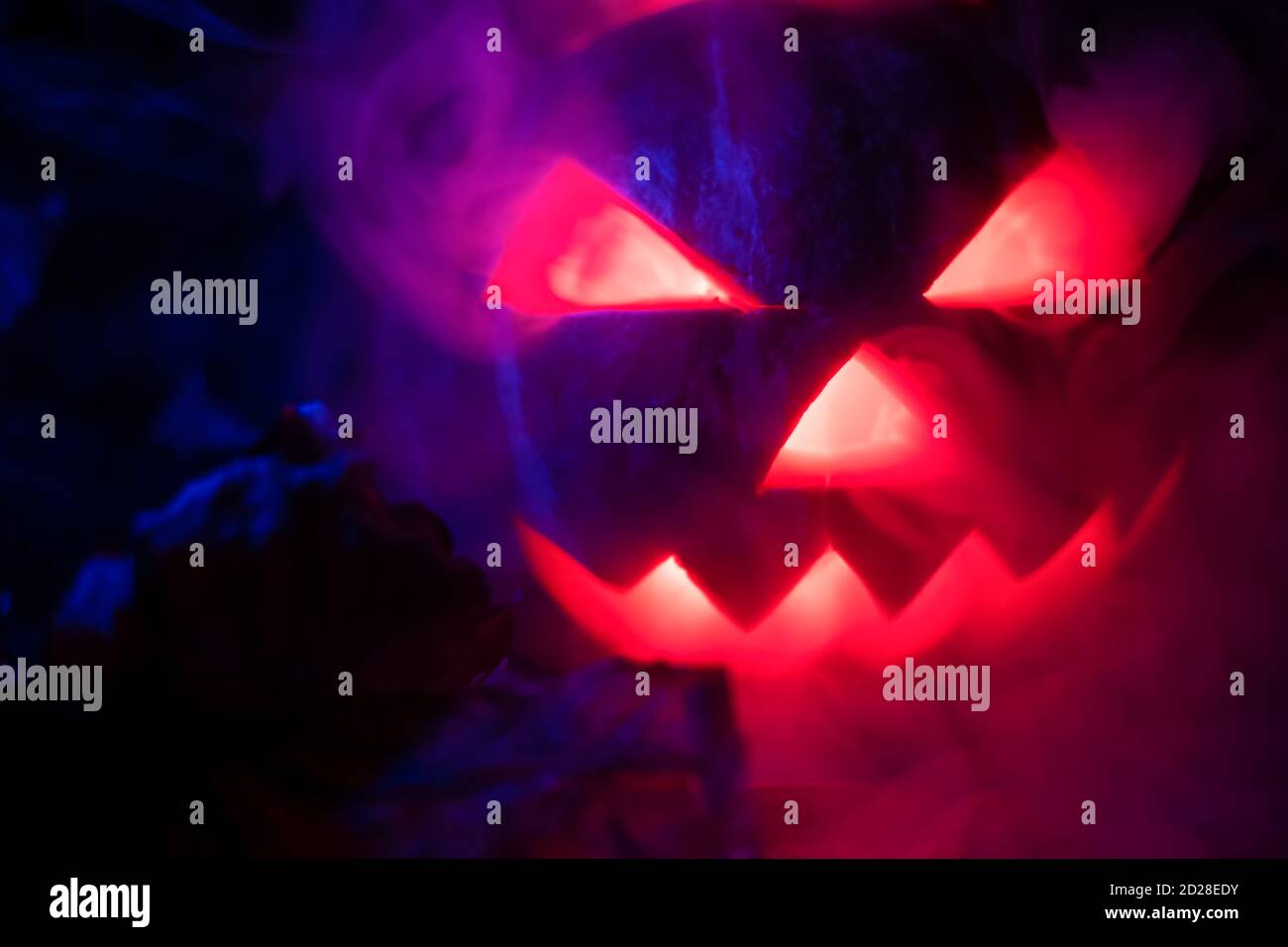 Zucca incandescente al buio che rilascia fumo dagli occhi e dalla bocca da vicino. Sfondo per Halloween. Foto Stock
