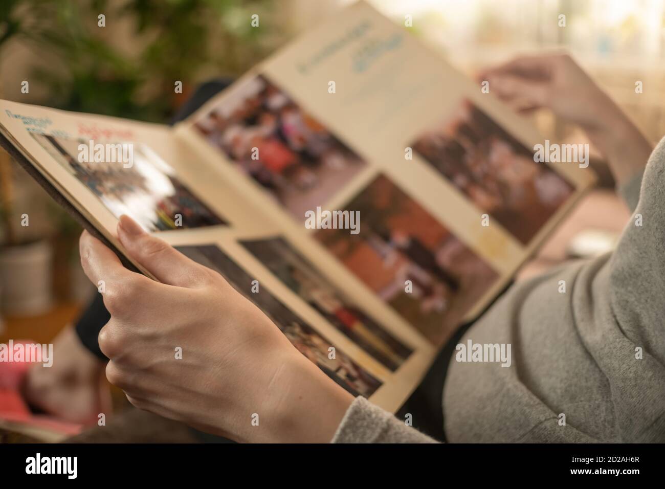 ragazza in una giacca grigia è seduta sul divano e guardando le vecchie foto in un album fotografico Foto Stock