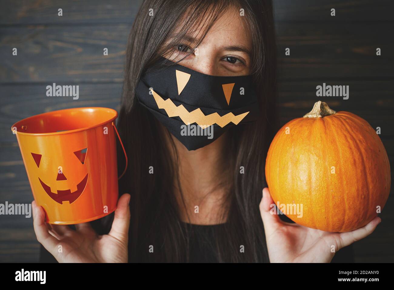 Halloween 2020 trucco o trattare. Donna felice in maschera nera male faccia  che tiene zucca e jack o lanterna secchio. Coronavirus halloween: Soggiorno  creativo, sta Foto stock - Alamy