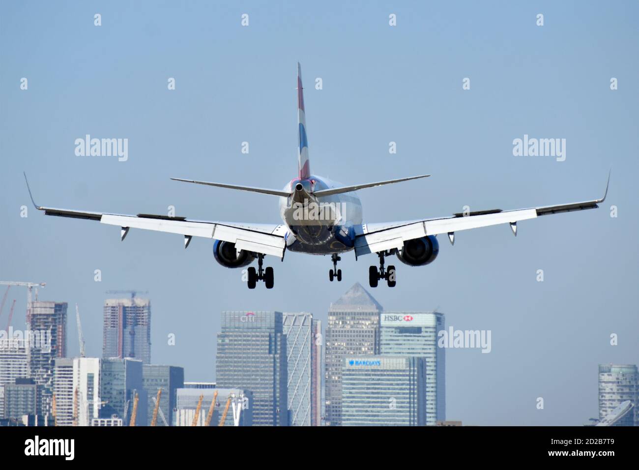 British Airways atterraggio aereo East London City Airport con Canary Wharf moderno skyline urbano a Londra Docklands oltre Newham Inghilterra UK Foto Stock
