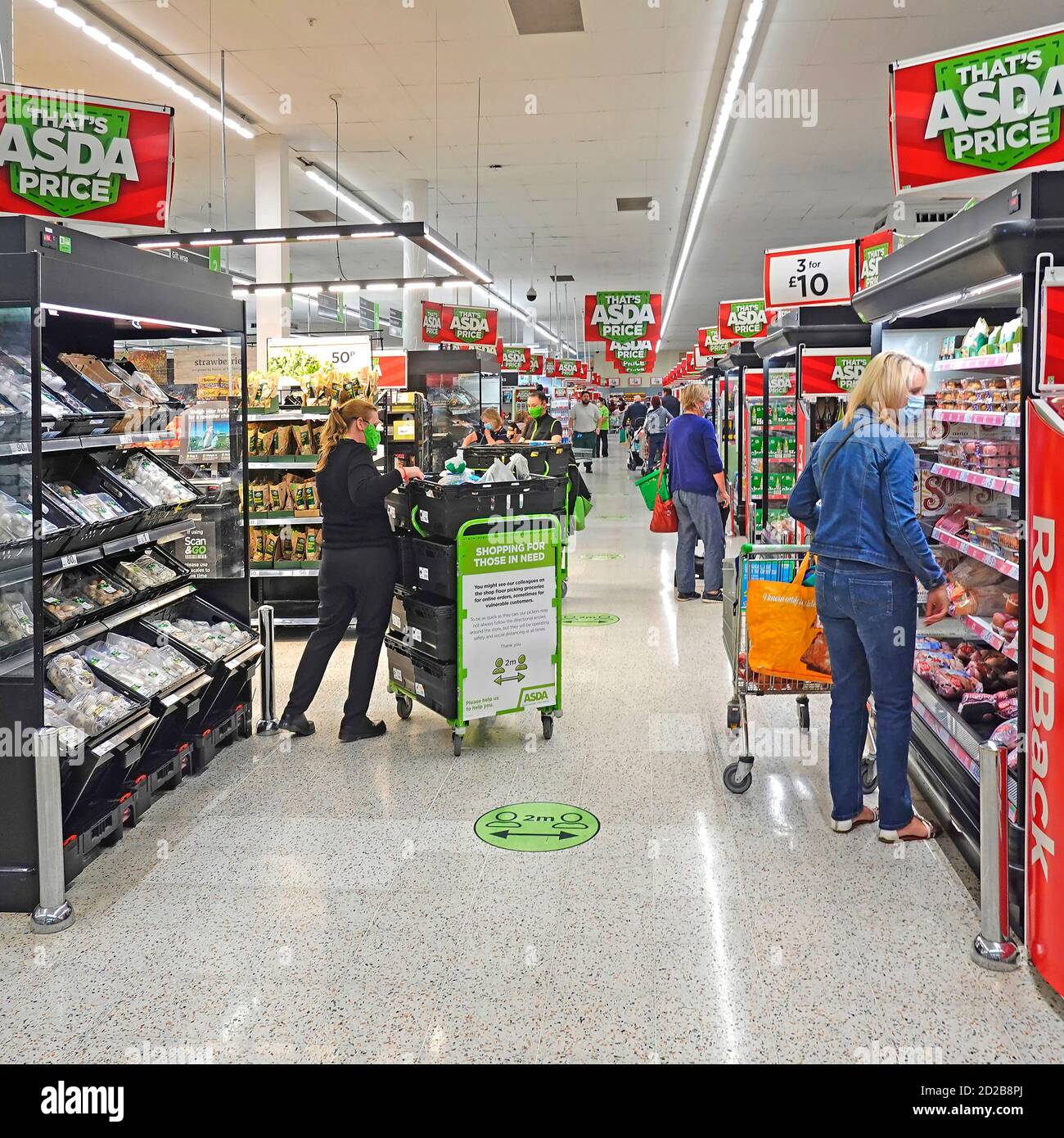 Il personale di acquisti del Coronavirus in Covid 19 maschere facciali Asda supermercato negozio alimentare corona virus sociale distanziando il personale di selezione e di indossare Maschera Inghilterra UK Foto Stock