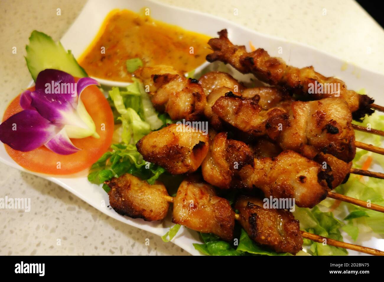 Deliziosi pezzi di pollo presentati con salsa satay e insalata di fiori, Hong Kong Foto Stock